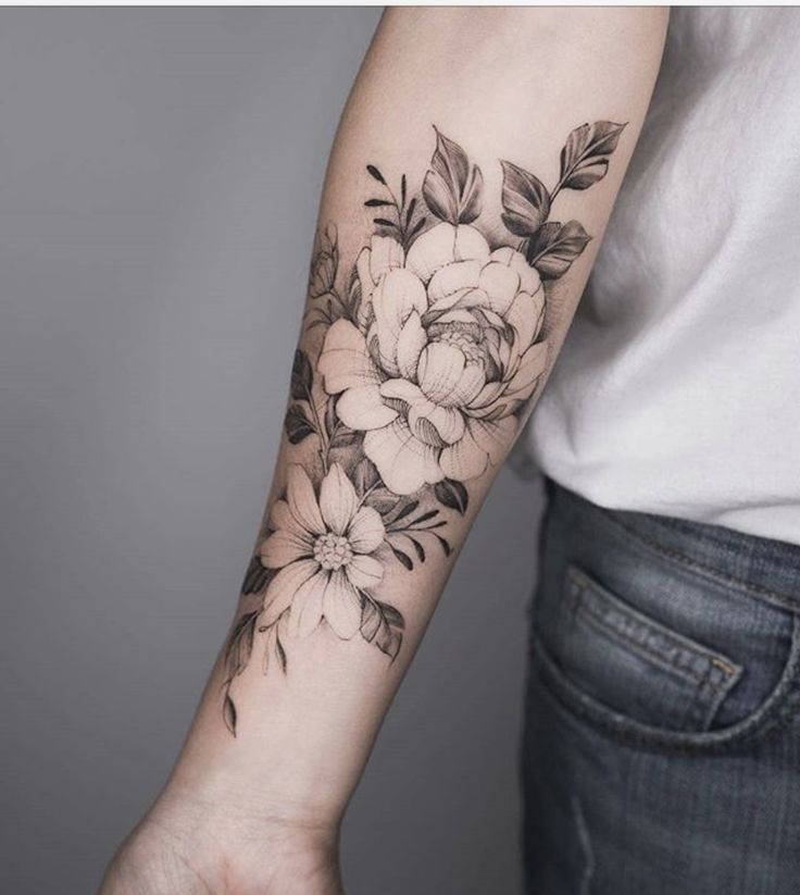 a woman's arm with flowers and leaves tattooed on the left side of her arm