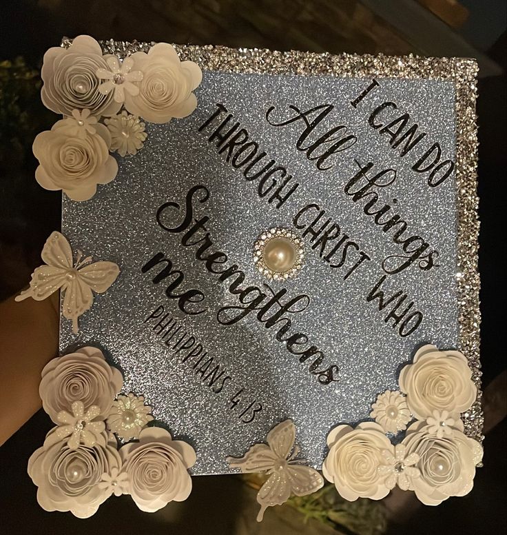 a graduation cap decorated with flowers and writing on the front is shown in silver glitter