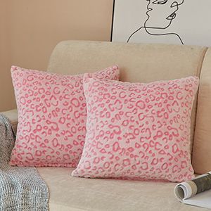 two pink leopard print pillows sitting on a couch next to a rolled up pillow case