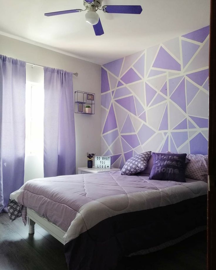 a bedroom with purple and white decor on the walls, ceiling fan in the corner