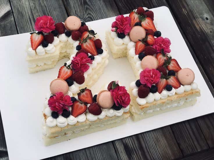 a white plate topped with a slice of cake covered in berries and cream frosting