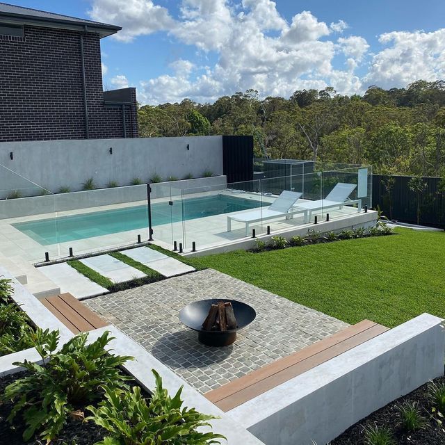 an outdoor swimming pool surrounded by grass and trees