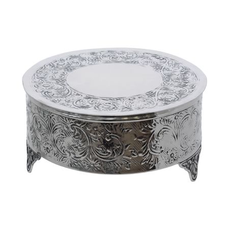 an ornate silver plate with floral designs on the top and bottom, sitting on a stand