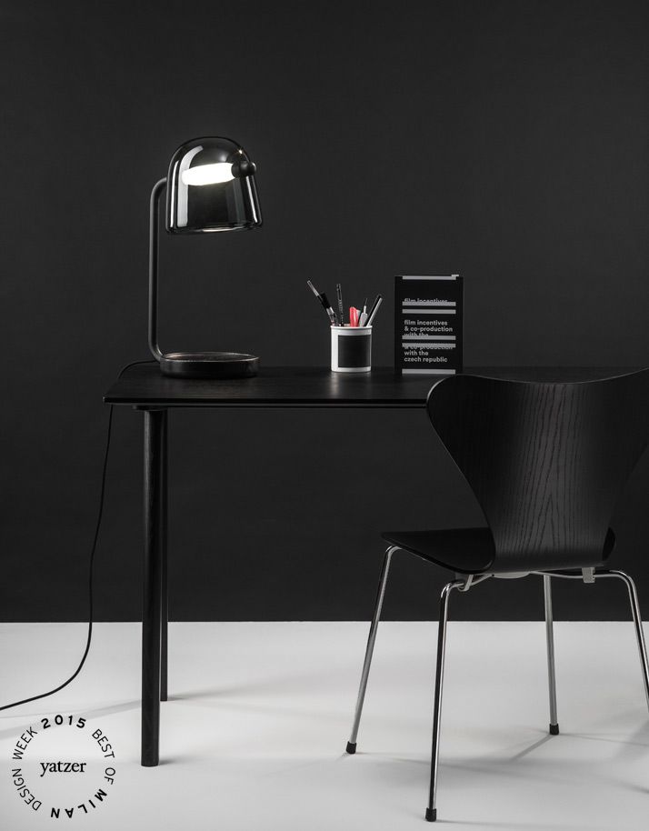 a black desk with a lamp on it and a book sitting next to the table