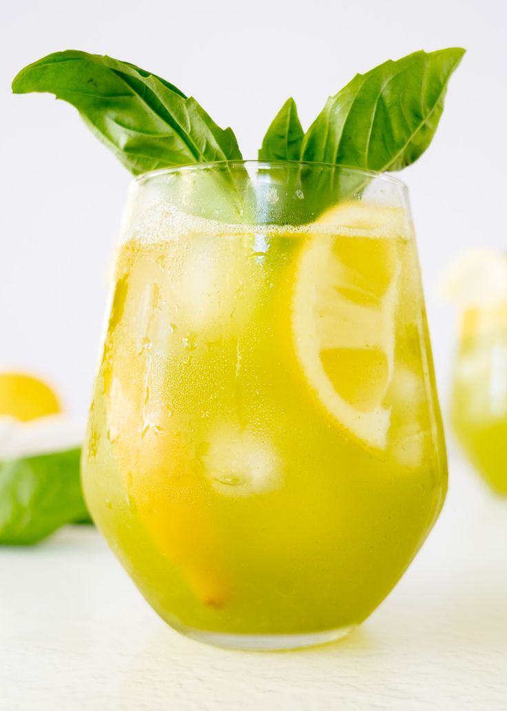 a glass filled with lemonade and garnished with green leafy leaves on top