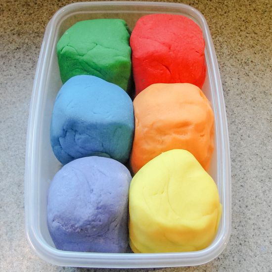 rainbow play dough in a plastic container on the counter and then placed in a baking dish