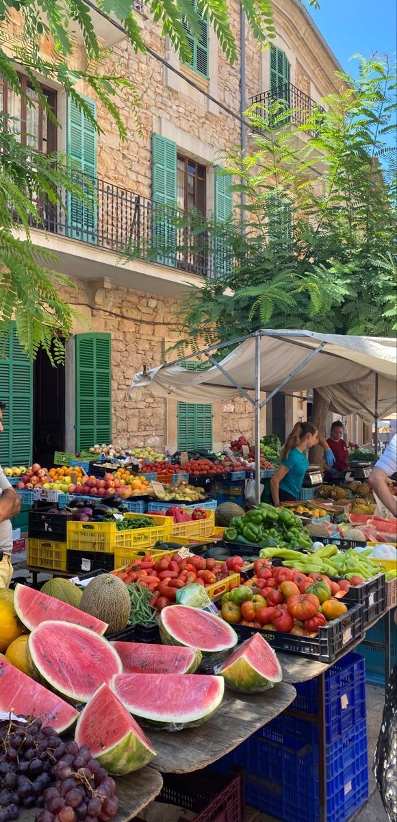 people shopping at an outdoor fruit market with watermelon, melons and other fruits