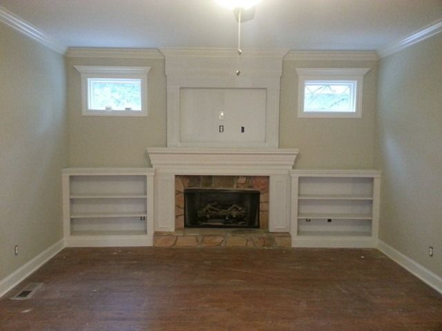 empty living room with fireplace and built - in bookcases