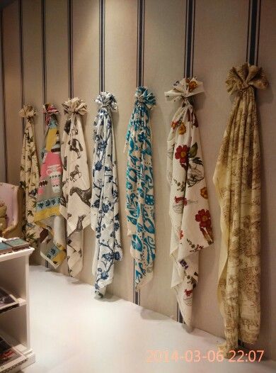 there are many scarves hanging on the wall next to each other in this room