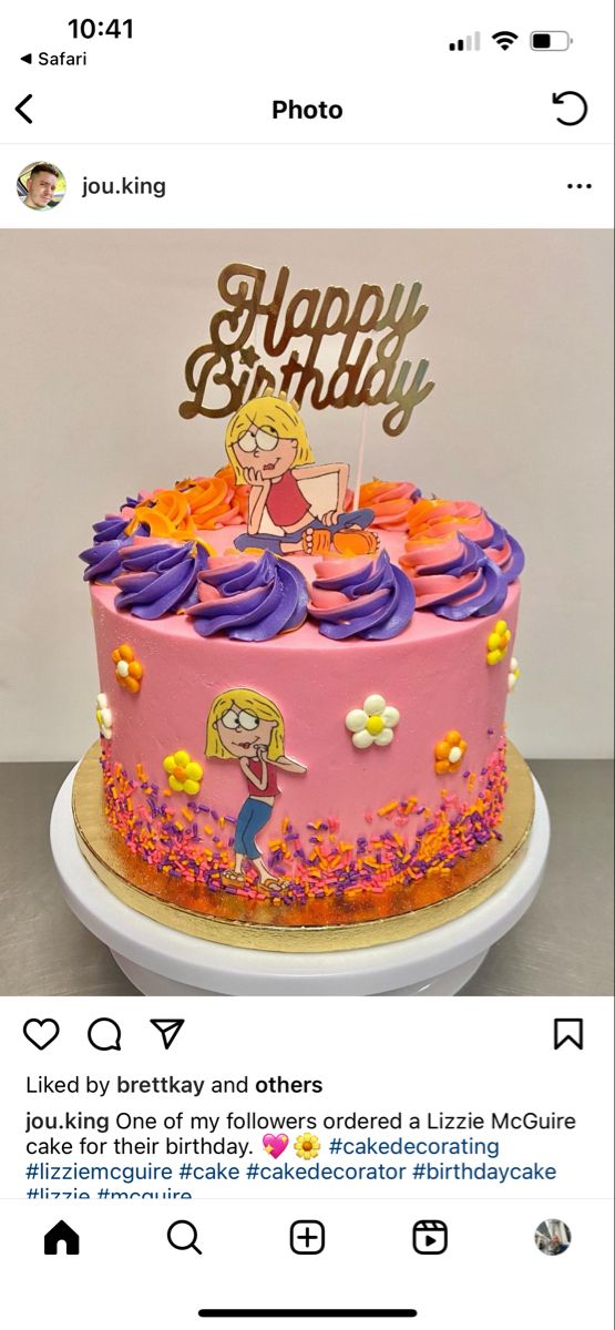 a pink birthday cake with purple frosting and a cartoon character on top, sitting on a table