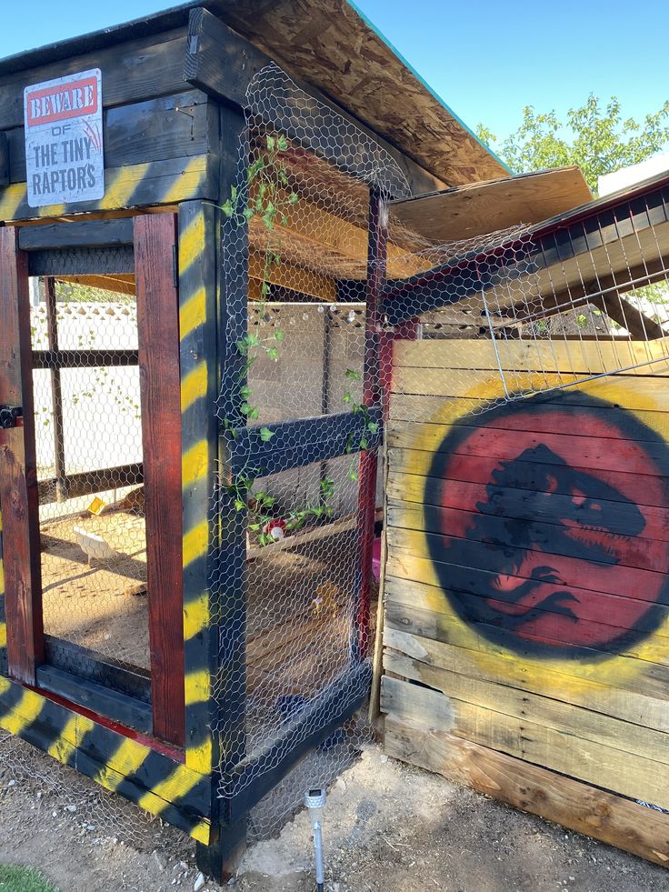 a chicken coop painted with an image of a lizard on it's side and the door open