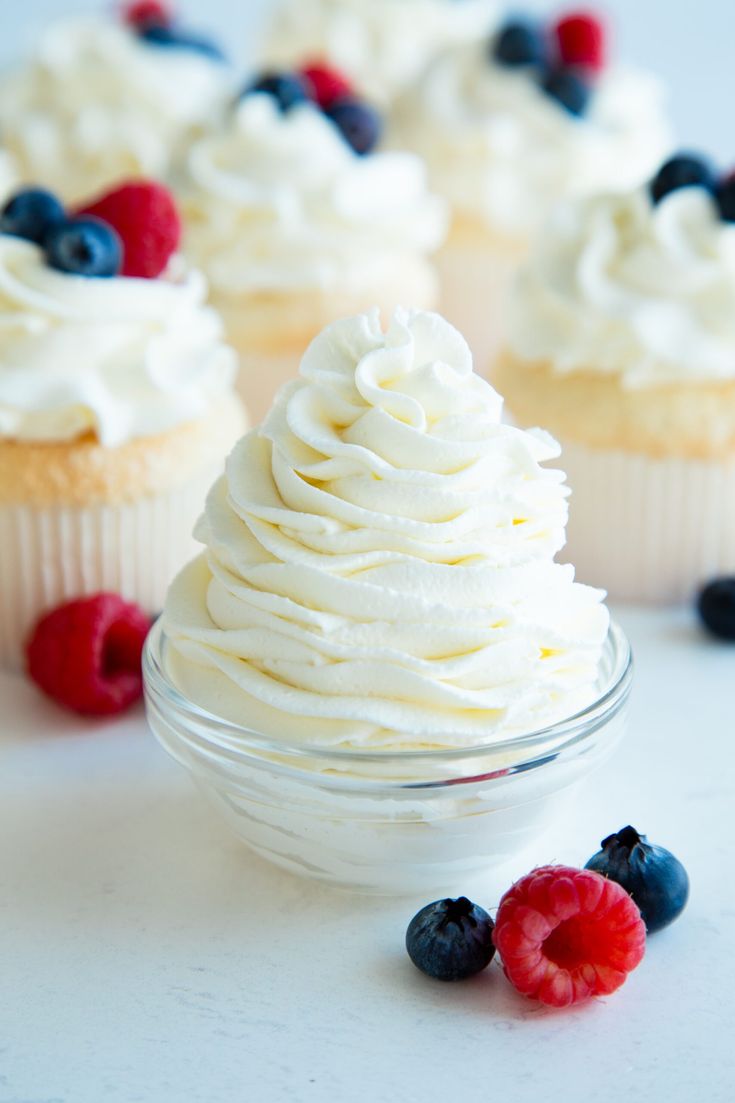 cupcakes with white frosting and berries on the side