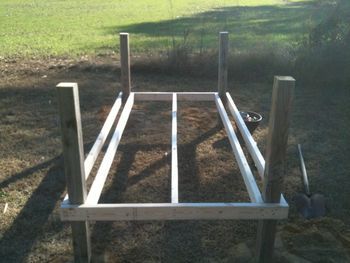 a wooden bed frame sitting in the middle of a field