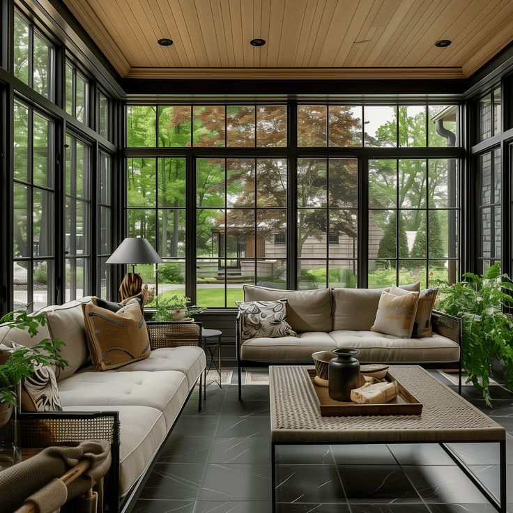 a living room filled with lots of furniture next to tall glass windows on the wall