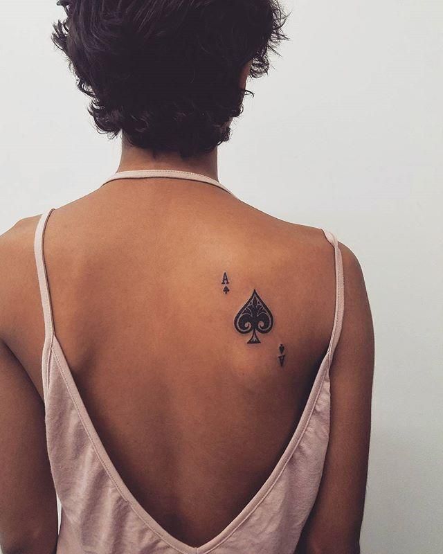 the back of a woman's neck with a tattoo on her left shoulder and an ace playing card