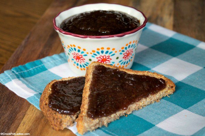 two pieces of bread sit on a blue and white checkered tablecloth next to a bowl of chocolate spread