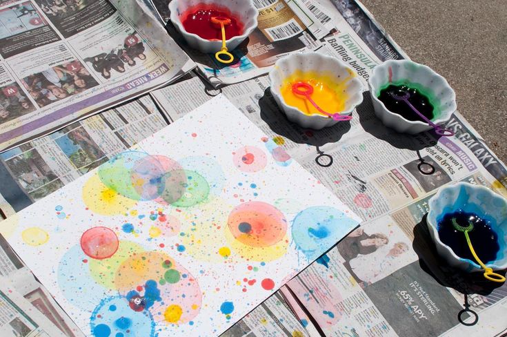 three bowls filled with different colored paint sitting on top of a newspaper next to each other