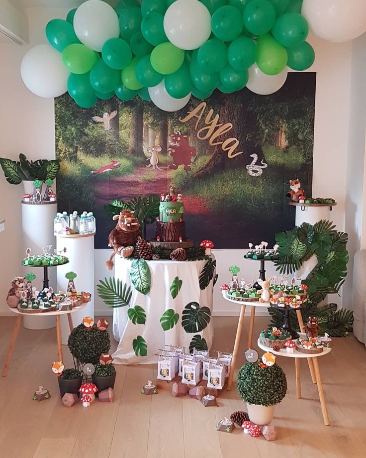 a party with green balloons and decorations on the wall, including tableware for desserts