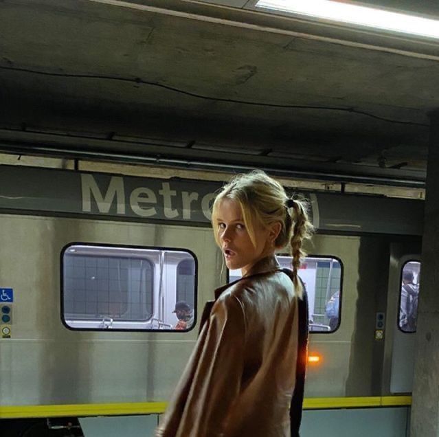 a woman standing in front of a train at the station with her back to the camera