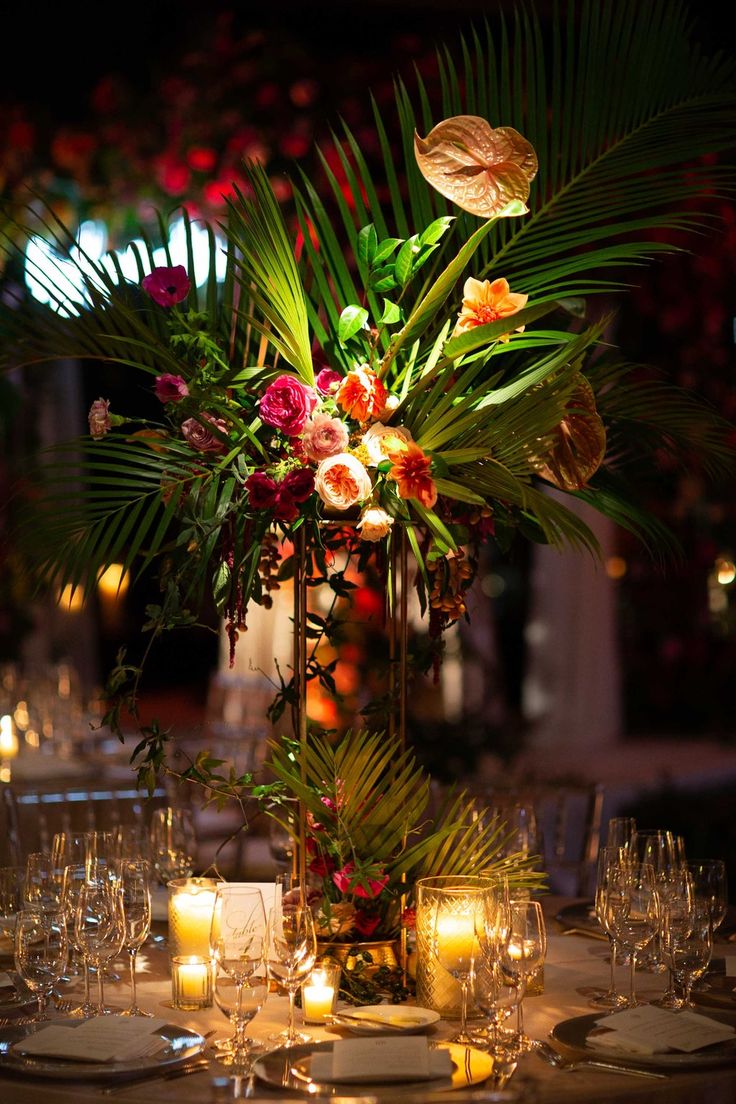 a vase filled with lots of flowers sitting on top of a table covered in candles