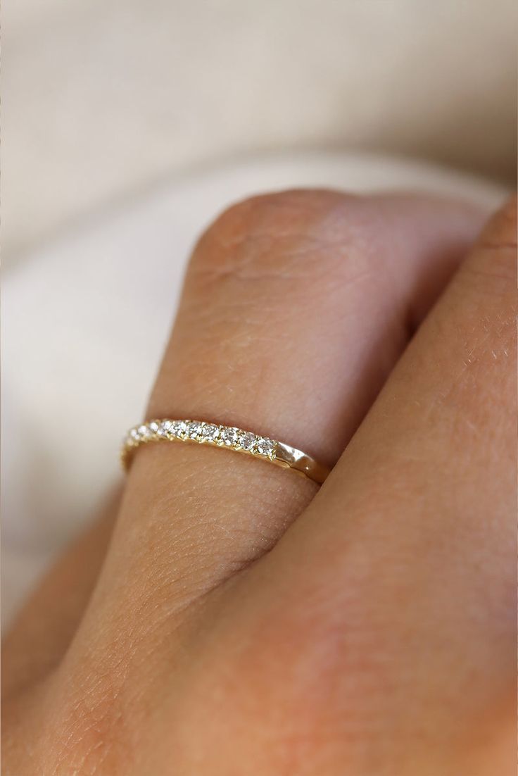 a woman's hand with a gold ring on her left side and the other half of her finger