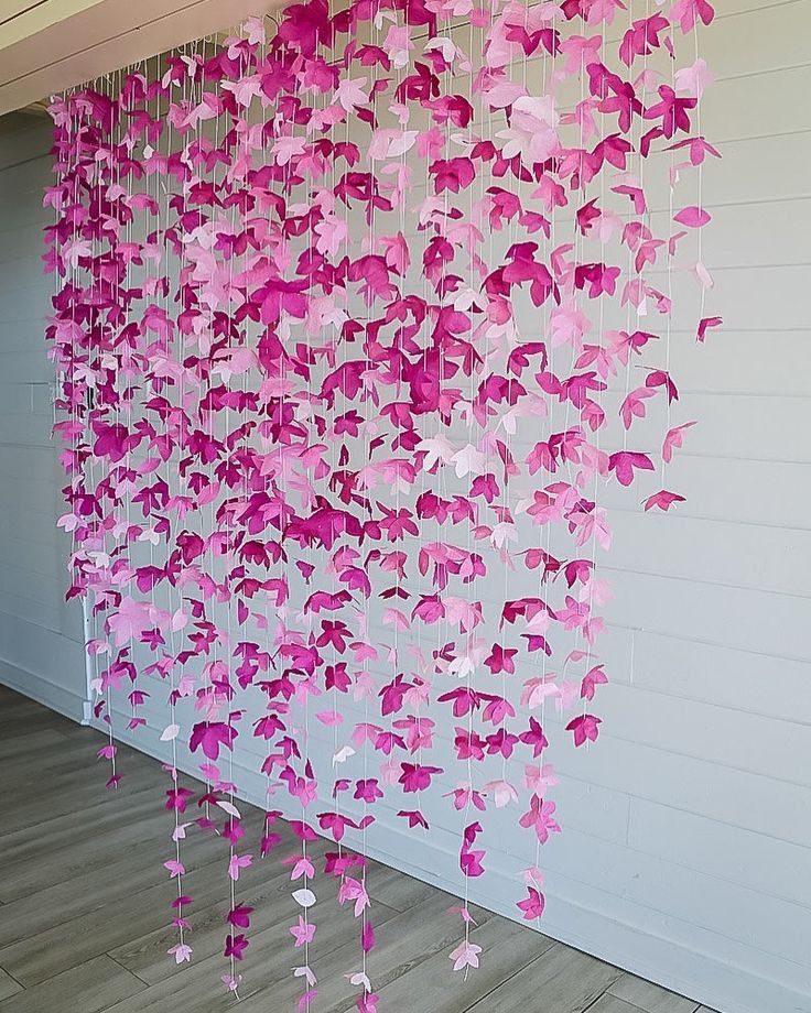 pink paper butterflies hanging from the side of a building