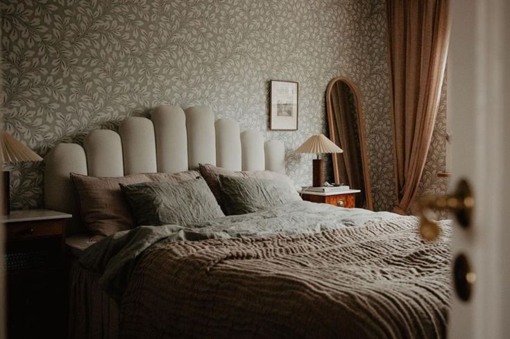 a large bed sitting next to a window in a room with curtains on the windowsill