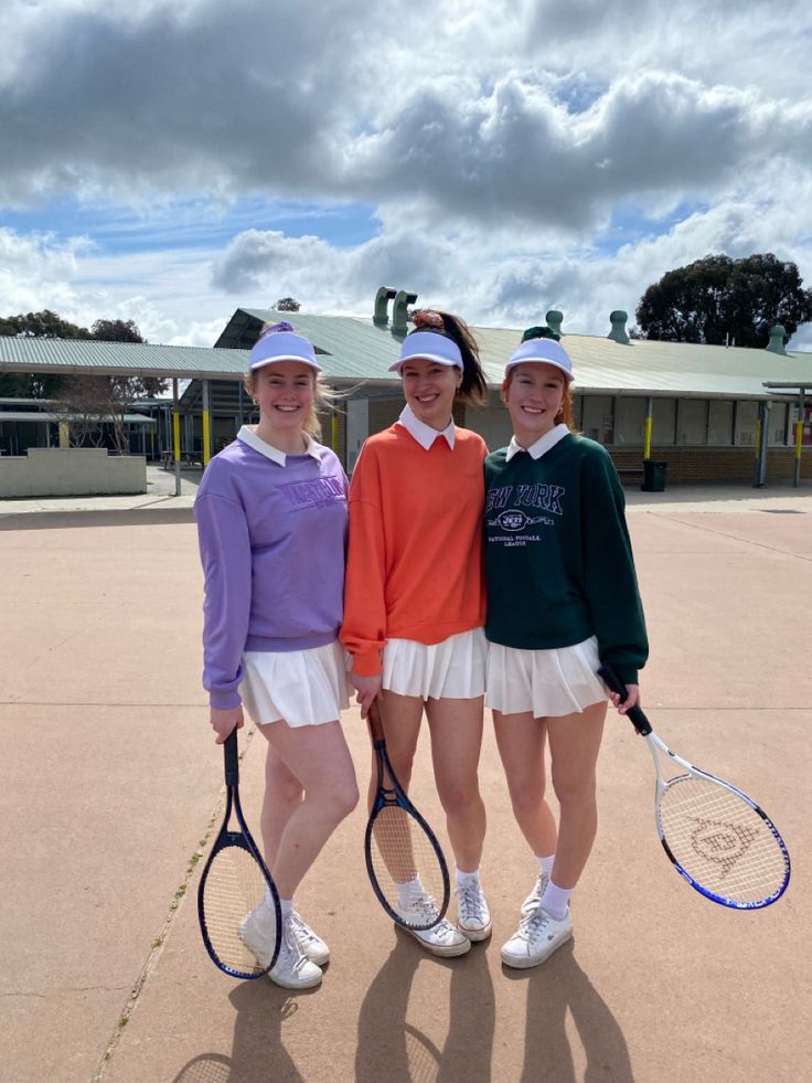 three girls in tennis outfits posing for the camera with their rackets and hats on