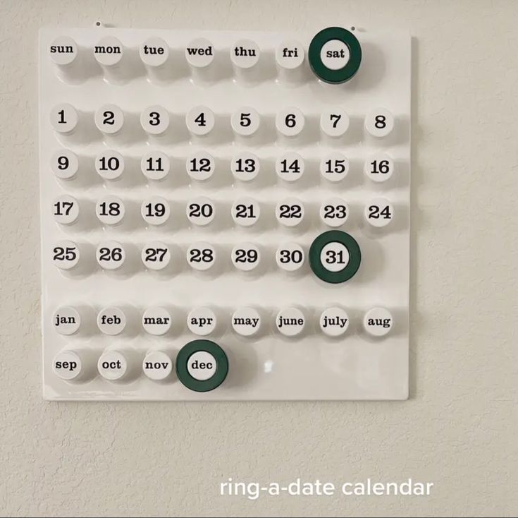 a white calendar with green circles on the front and numbers on the back, hanging on a wall