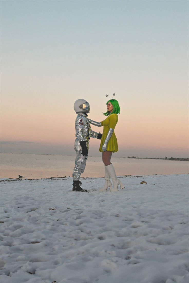 two people in space suits are standing on the beach and one is shaking hands with the other