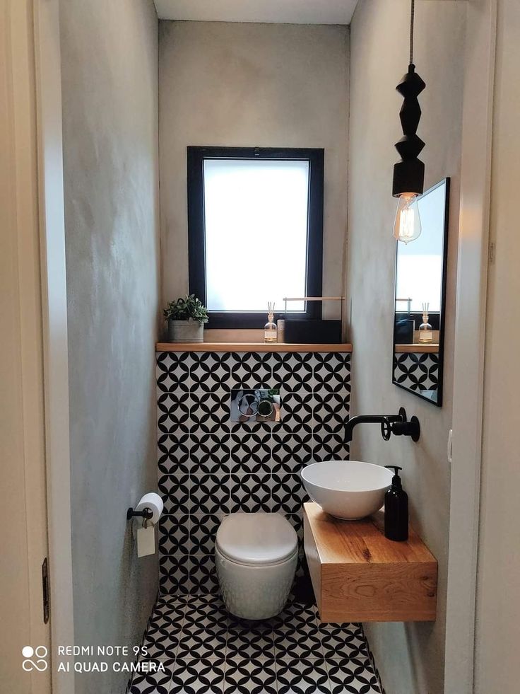 a bathroom with black and white tiles on the floor, sink and toilet in it