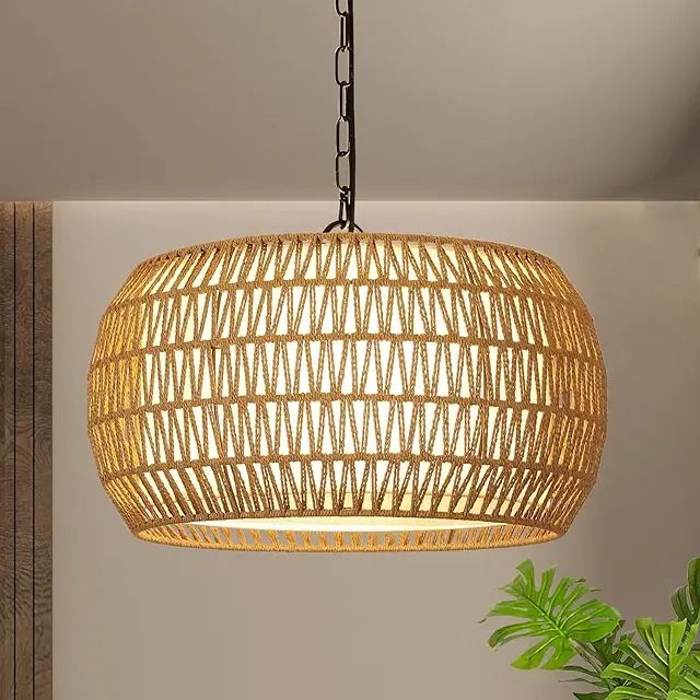 a large rattan light fixture hanging from a ceiling in a room with a potted plant