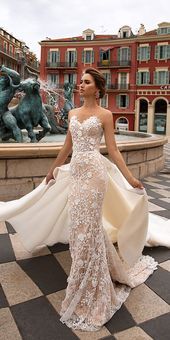 a woman standing in front of a fountain wearing a wedding dress