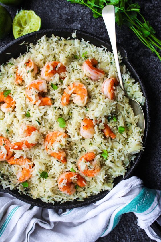 shrimp rice in a skillet with limes and cilantro on the side