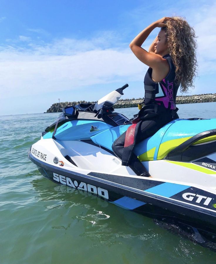 a woman sitting on the back of a blue and white jet ski in the ocean