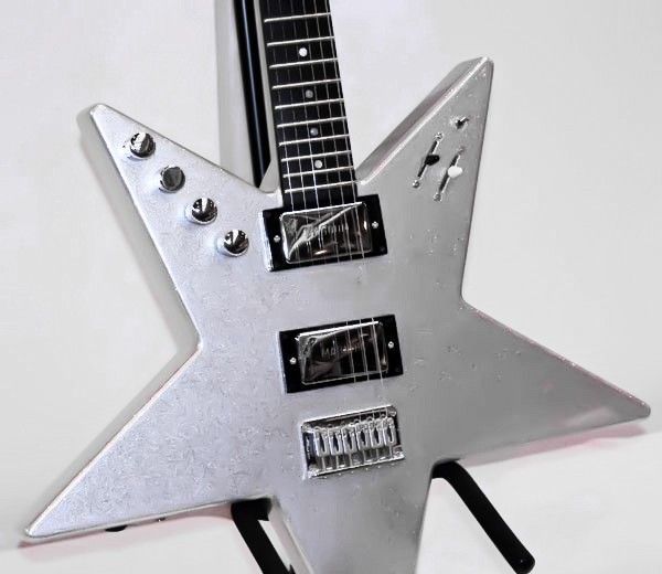 a metal star shaped object with multiple knobs on it's sides and an electric guitar in the middle