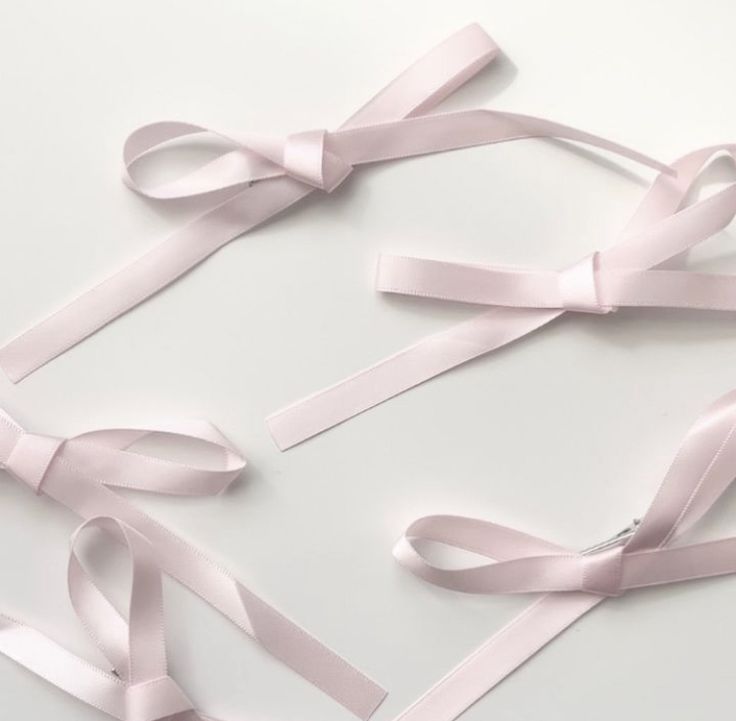 several pink ribbons tied together on a white surface