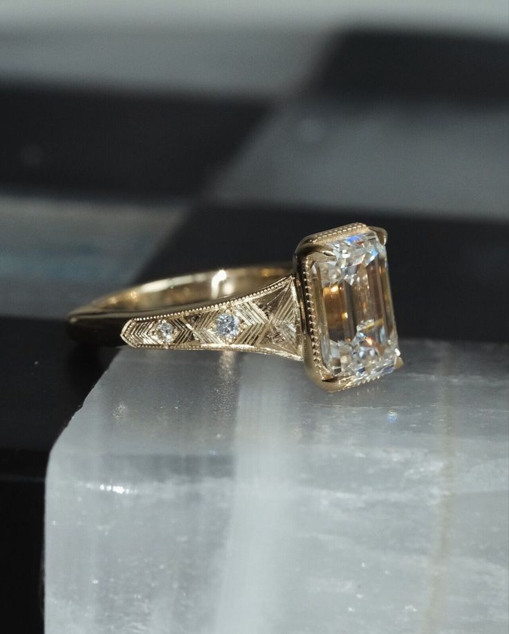 an antique style diamond ring on top of a clear crystal block with diamonds around it