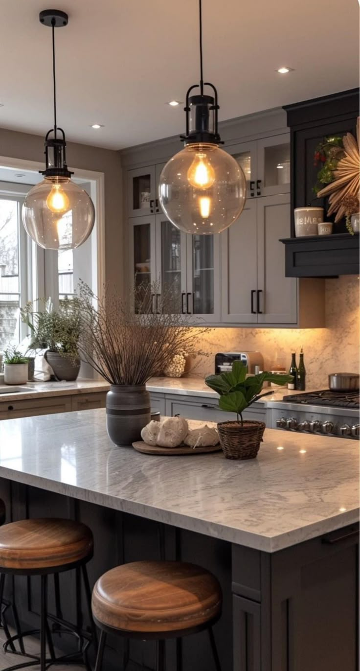 a kitchen island with stools and lights hanging from it's ceiling over the counter