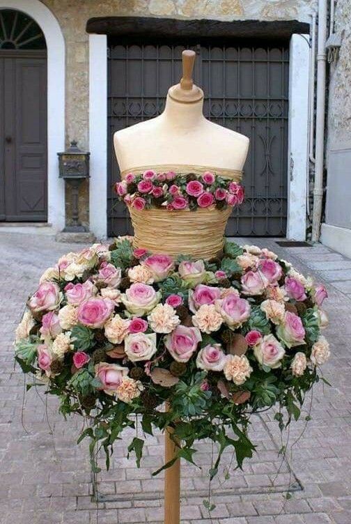 a mannequin is covered with flowers in front of a brick wall and door