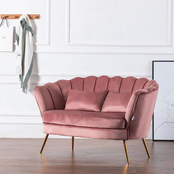 a pink chair sitting on top of a hard wood floor next to a white wall