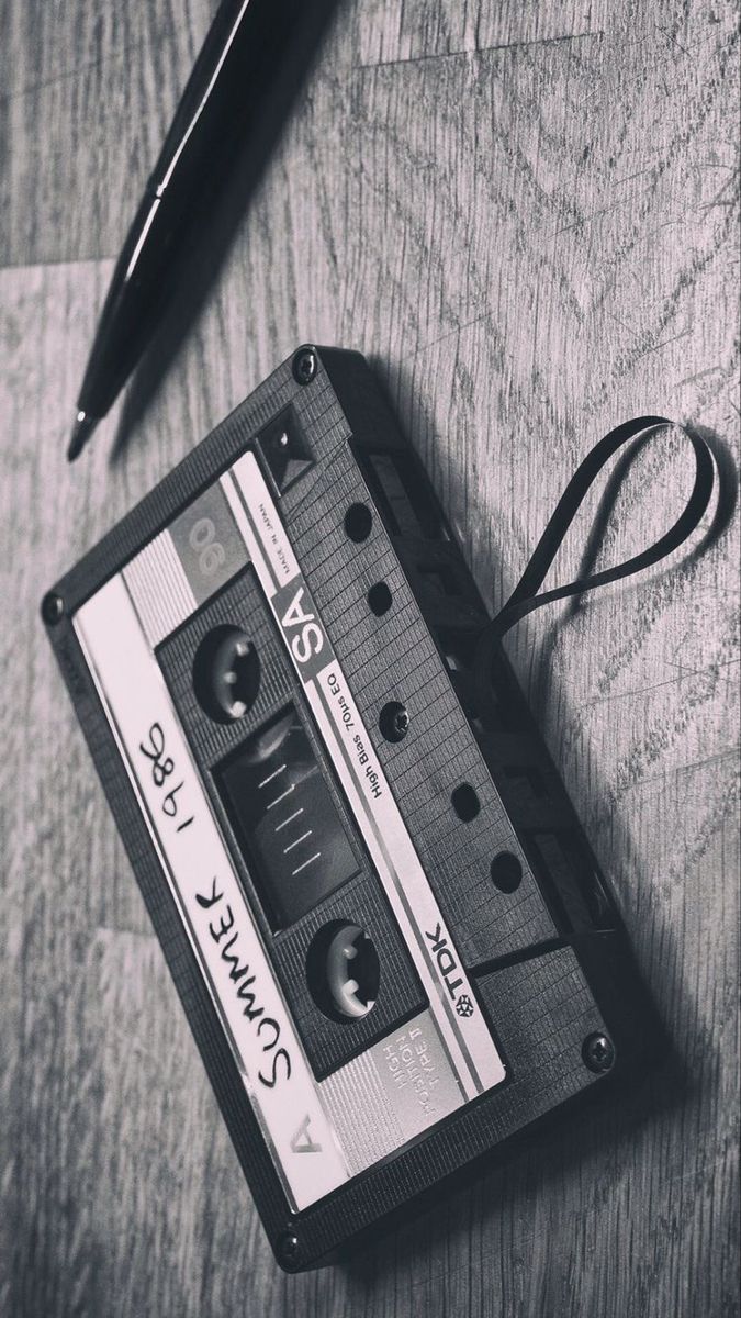 an old fashioned cassette tape recorder sitting on top of a table next to a pen