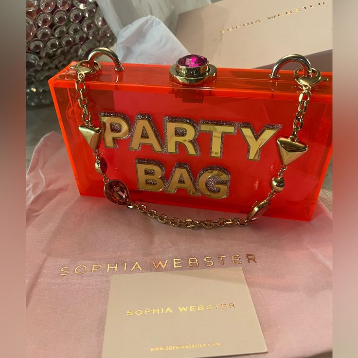 Sophia Webster Cleo Party Bag Clutch Neon Redish Pink And Gold Comes With The Dust Bag And Box The Name Says It All With This Festive Multicolor Clutch Boasting A Removable Straps And Polished Lettering That's Sure To Draw Attention. 8"W X 4 1/4"H X 1 1/2"D 4" Strap Drop Magnetic Frame Closure Acrylic Imported Trendy Party Clutch With Dust Bag Included, Trendy Party Clutch With Dust Bag, Trendy Top Handle Clutch For Party, Trendy Red Clutch For Parties, Trendy Red Party Clutch, Designer Evening Bag For Party, Chic Party Bags, Designer Clutch Bag For Party, Chic Party Clutch With Top Handle