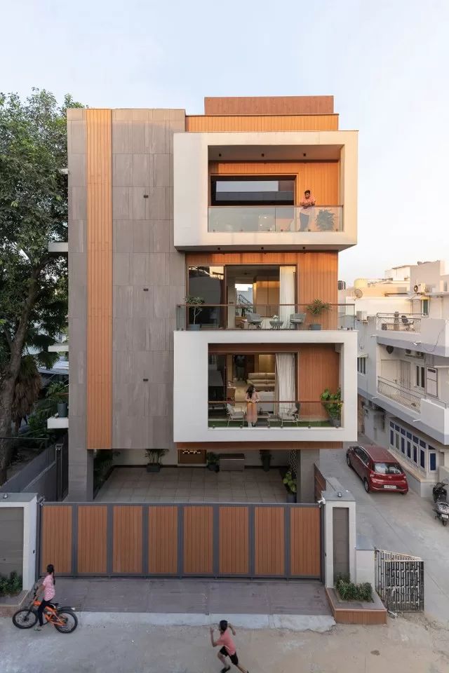 two people walking on the sidewalk in front of a modern building with multiple levels and balconies