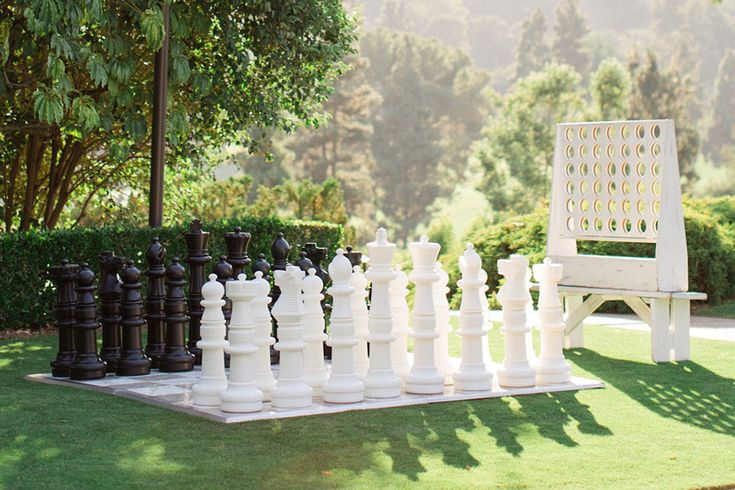 a giant chess set sitting on top of a grass covered field next to a park bench