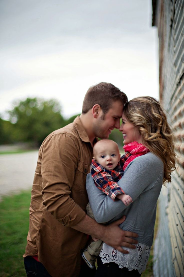 a man and woman holding a baby in front of a barn with the caption from family kreae