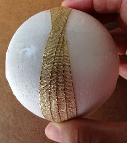 a person is holding an ornament made out of white and gold foil strips