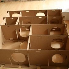 several cardboard boxes sitting on the floor in front of a cat scratching box with holes