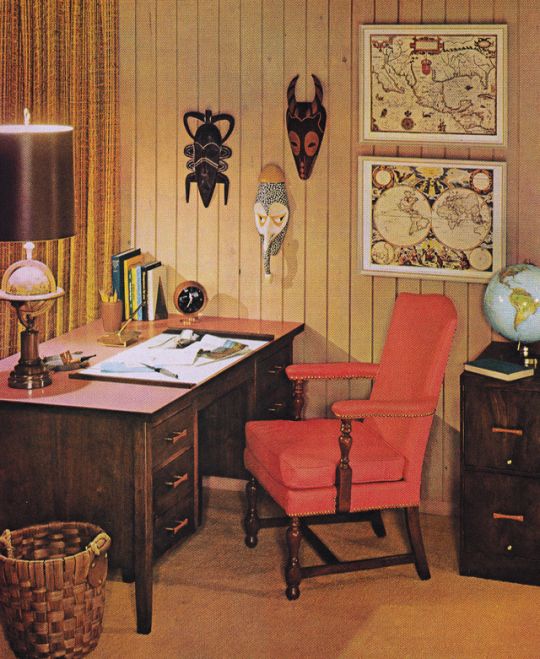 an old fashioned desk with a red chair in front of it and pictures on the wall