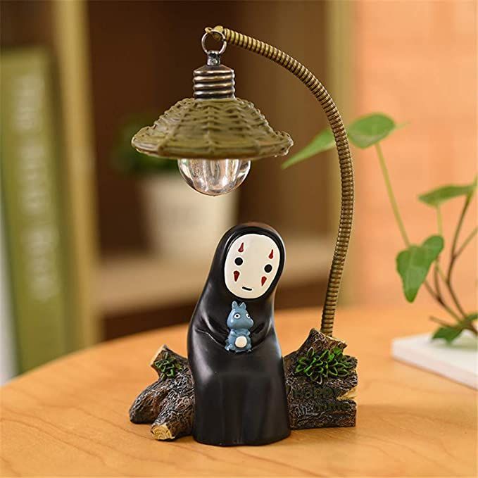 a small figurine sitting on top of a wooden table next to a lamp